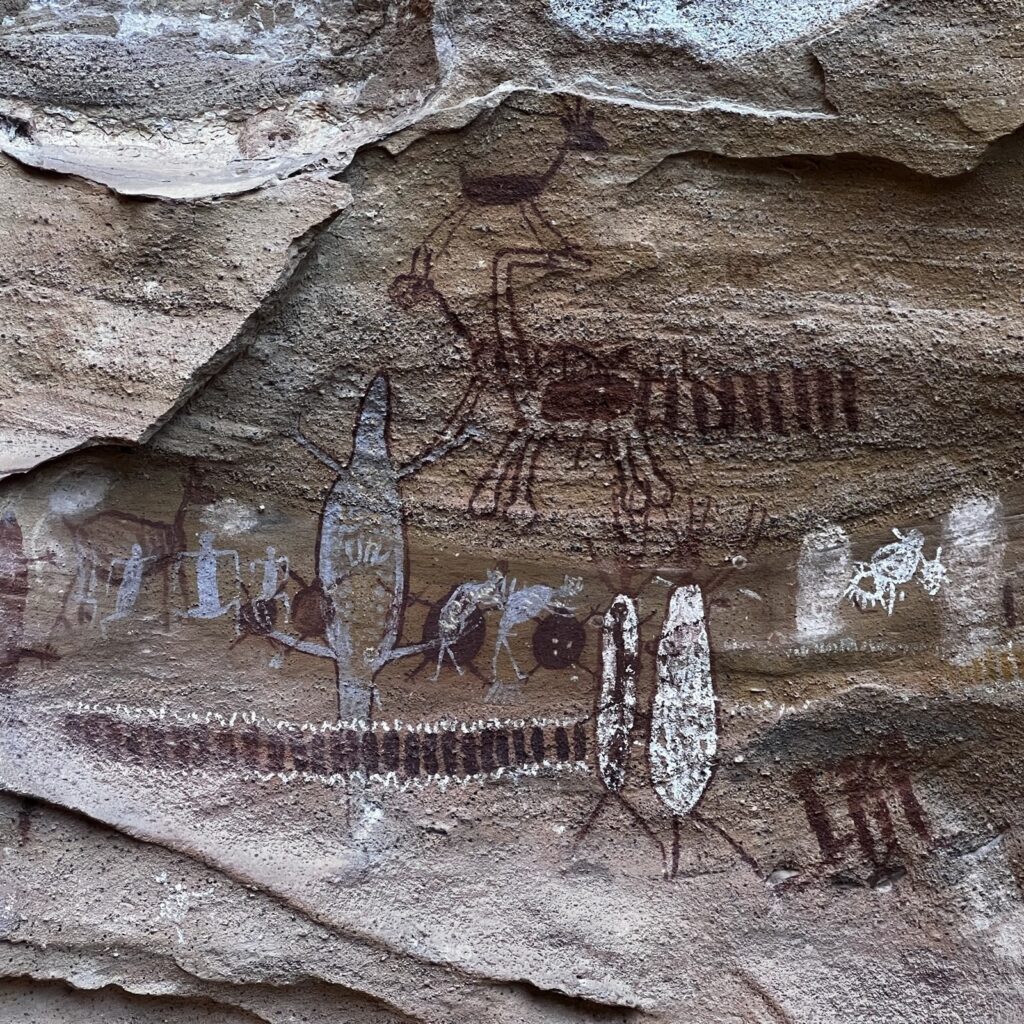 Painel de pinturas rupestres na Serra da Capivara, com figuras humanas e animais em vermelho e branco